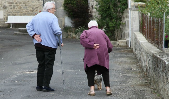 two older people helping each other