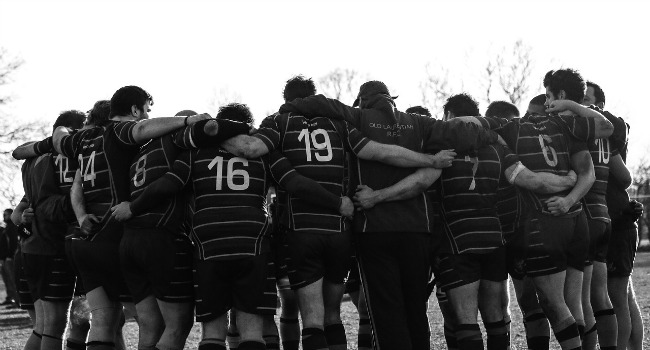 rugby team with arms around each other in a huddle